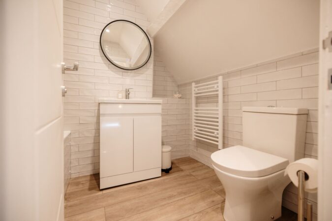 Main family bathroom with full-size bathtub, overhead shower, and modern tiling at The Hideaway