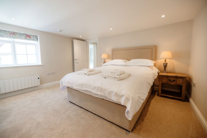 Spacious king-size bedroom with crisp white linens and cozy decor at The Hideaway