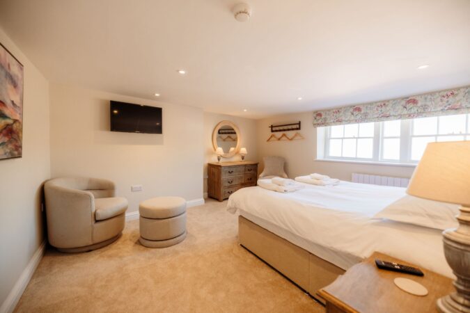 Stylish king-size bedroom with soft coastal-themed decor at The Hideaway in Whitby